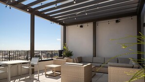 A rooftop terrace with outdoor furniture, a pergola with string lights, and a view of the cityscape. - Hilton Garden INN Greenville University (Greenville)