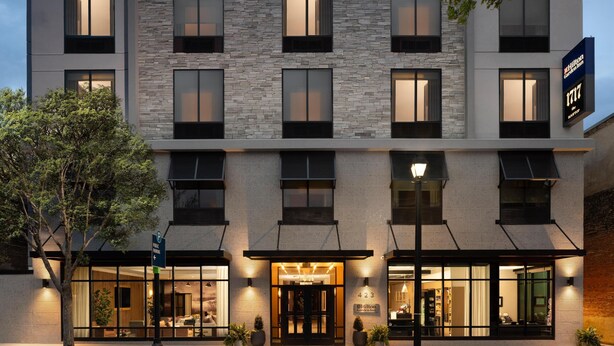 A modern hotel with a stone facade, large windows, and a well-lit entrance. - Hilton Garden INN Greenville University (Greenville)