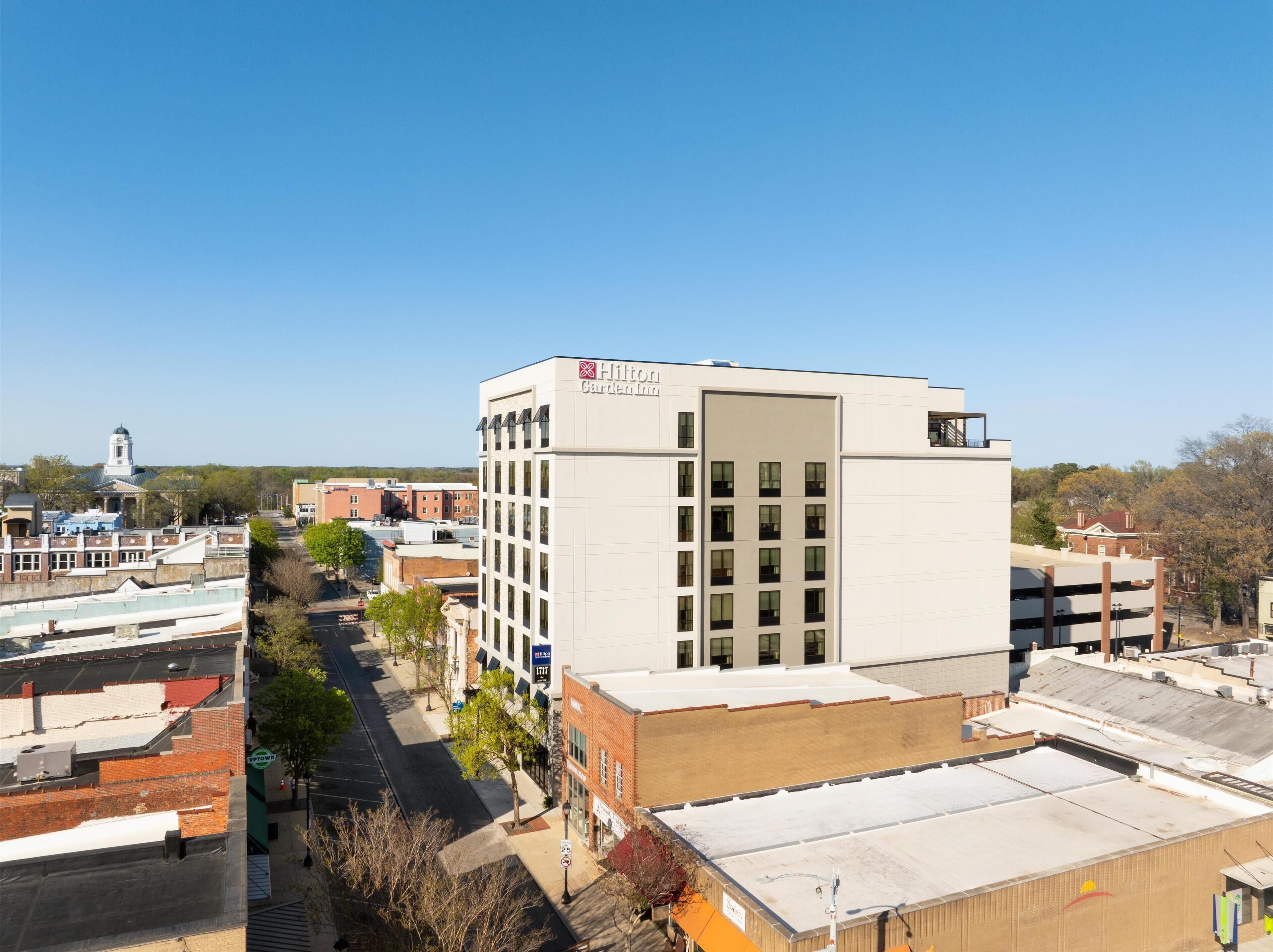 A modern hotel with a flat roof, multiple floors, and a prominent sign.