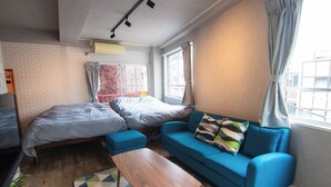 A modern bedroom with a bed, a blue sofa, a wooden coffee table, and a patterned rug. - Chateau Yoyogi 1-401 (Tokyo)