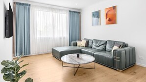 Ein modernes Wohnzimmer mit einem Ecksofa, einem runden Couchtisch und einem flachbildfernseher an der Wand.