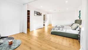 Ein modernes Schlafzimmer mit Holzboden, einem Bett mit grünem Kopfteil und einem kleinen runden Tisch mit Marmorplatte.