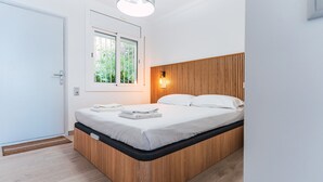 A modern bedroom with a wooden bed frame, a window with a view of greenery, and a bedside lamp. - WELCS APARTAMENTO 181 EMP con vistas al mar (Rosas / Roses)