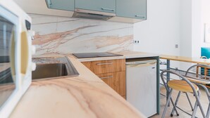 A modern kitchen with a marble backsplash, wooden cabinets, a built-in dishwasher, and a dining area with a chair and table. - WELCS APARTAMENTO 181 EMP con vistas al mar (Rosas / Roses)