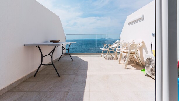 A balcony with a table and chairs, overlooking a body of water. - WELCS APARTAMENTO 181 EMP con vistas al mar (Rosas / Roses)