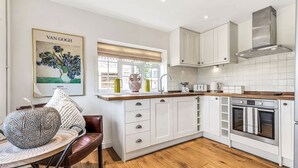 A modern kitchen with white cabinetry, a built-in oven, and a window with a view of the street.