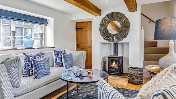 A cozy living room with a sofa, a round coffee table, a fireplace, and a large mirror.