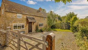 A stone house with a gravel driveway and a wooden gate.