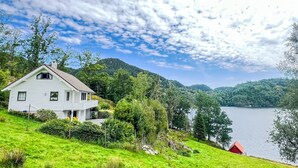 Ein weißes Haus mit einem roten Scheune, umgeben von üppiger Vegetation und einem See.