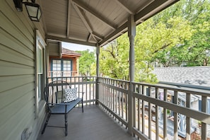 A covered porch with a bench and railing, overlooking a residential area with trees and houses. - 59 Cuna l Heart of Downtown | Hot Tub (St. Augustine)