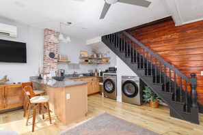 A modern kitchen with a central island, built-in appliances, and a staircase with a wooden finish. - 59 Cuna l Heart of Downtown | Hot Tub (St. Augustine)