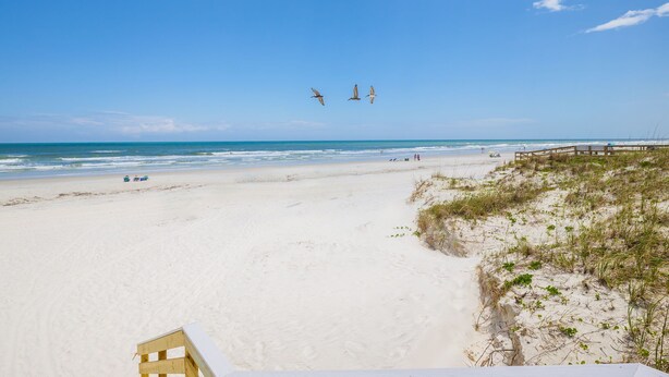 A beach with a wooden boardwalk, sandy beach, and ocean view.