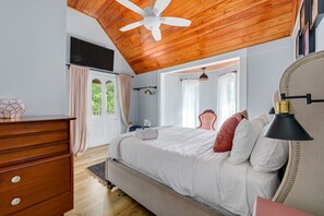 A bedroom with a wooden ceiling, a bed with white bedding, a dresser, and a window with curtains. - 59 Cuna l Heart of Downtown | Hot Tub (St. Augustine)