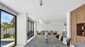 Un comedor moderno con una mesa de mármol, sillas grises e iluminación colgante.