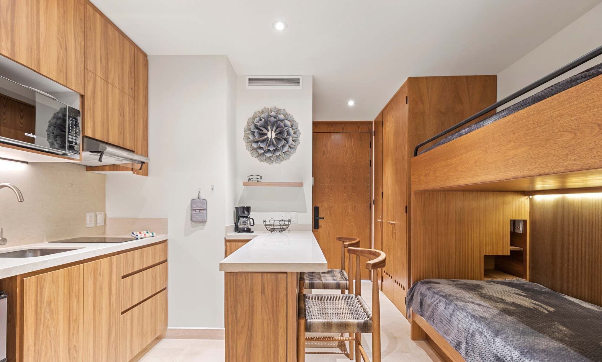 A compact kitchen with wooden cabinets, a central island, and a dining area with chairs.