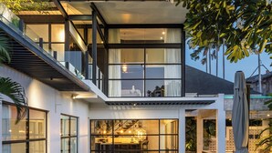 A modern two-story house with a spacious patio, a dining area, and a covered seating area. - Smeralda Villa (Canggu)