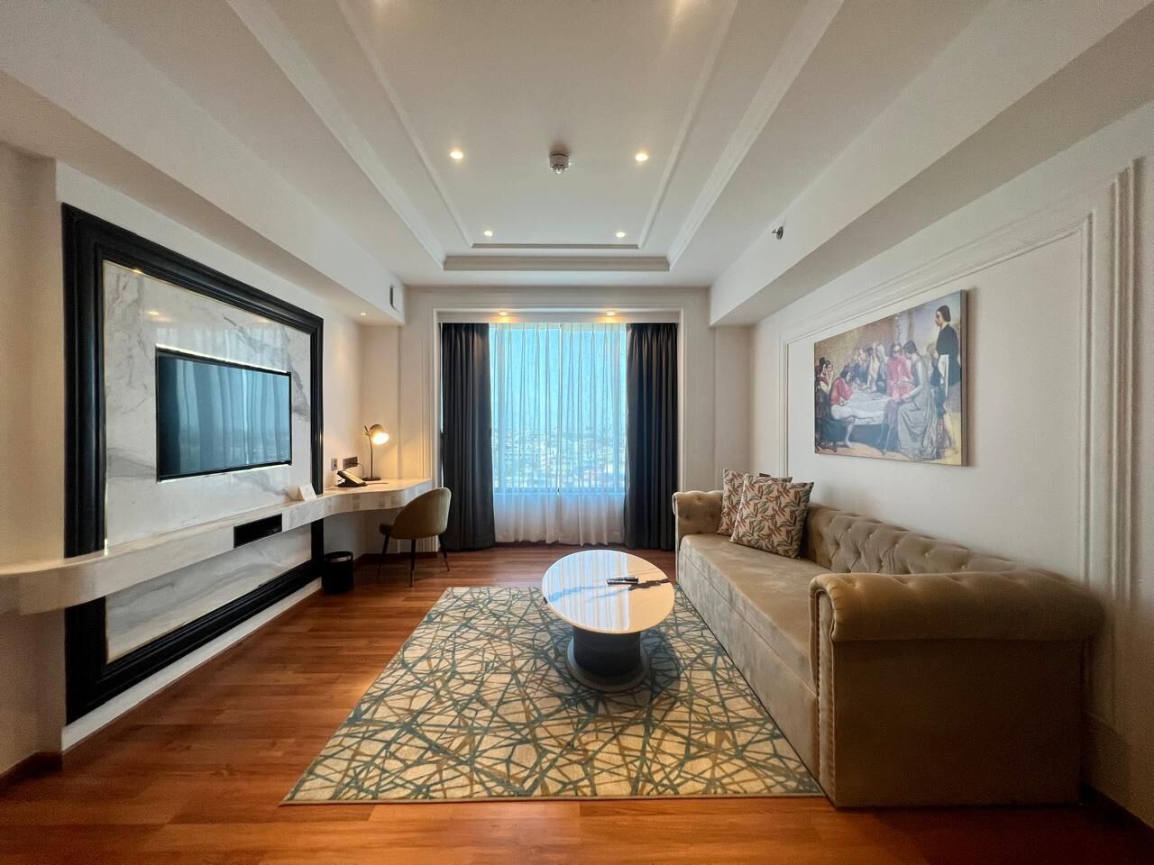 A modern living room with a flat-screen TV, a round coffee table, a sofa, and a dining area with a table and chairs.