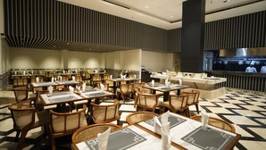 En rummelig restaurant med flere borde og stole, et moderne køkken og et gulv med et mønster.