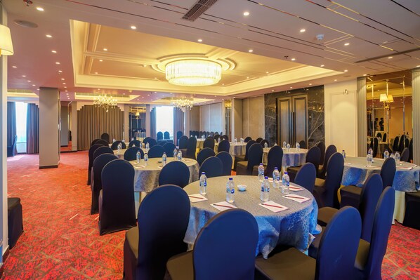 A conference room with round tables, chairs, and water bottles. - Hotel Soot (Barasat)