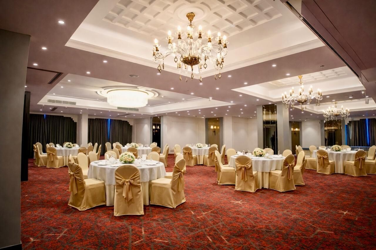 Un salón de banquetes con mesas redondas, sillas y candelabros.