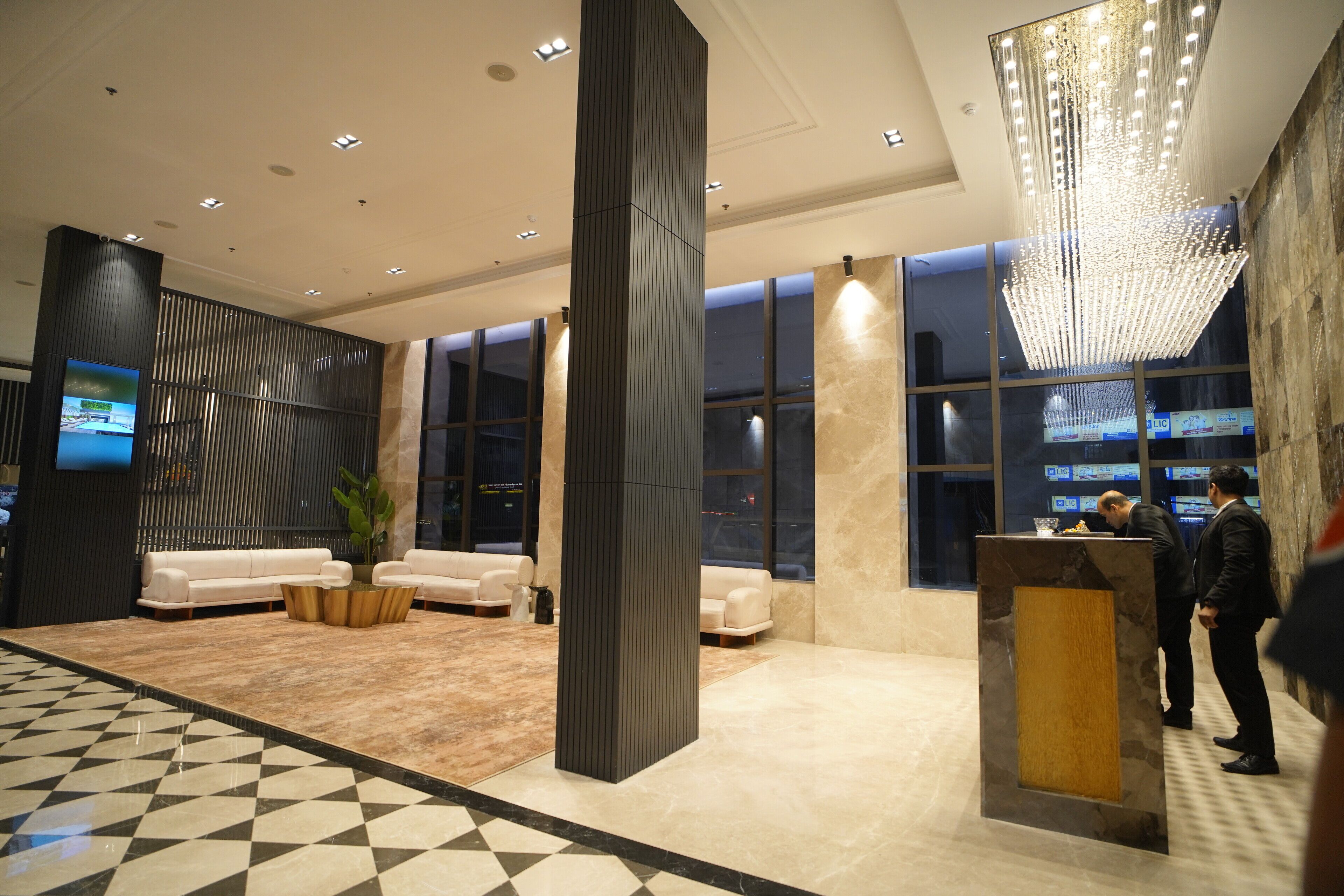 Eine moderne Lobby mit Schachbrettmuster-Boden, Sitzgelegenheiten und einer Rezeption.