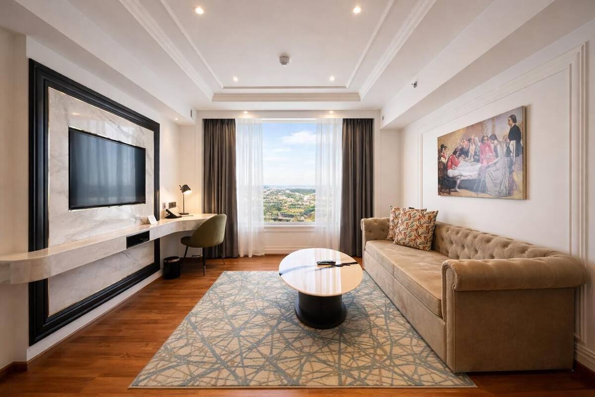 Een moderne woonkamer met een flatscreen televisie, een bank, een salontafel en een groot raam met uitzicht op de stad.