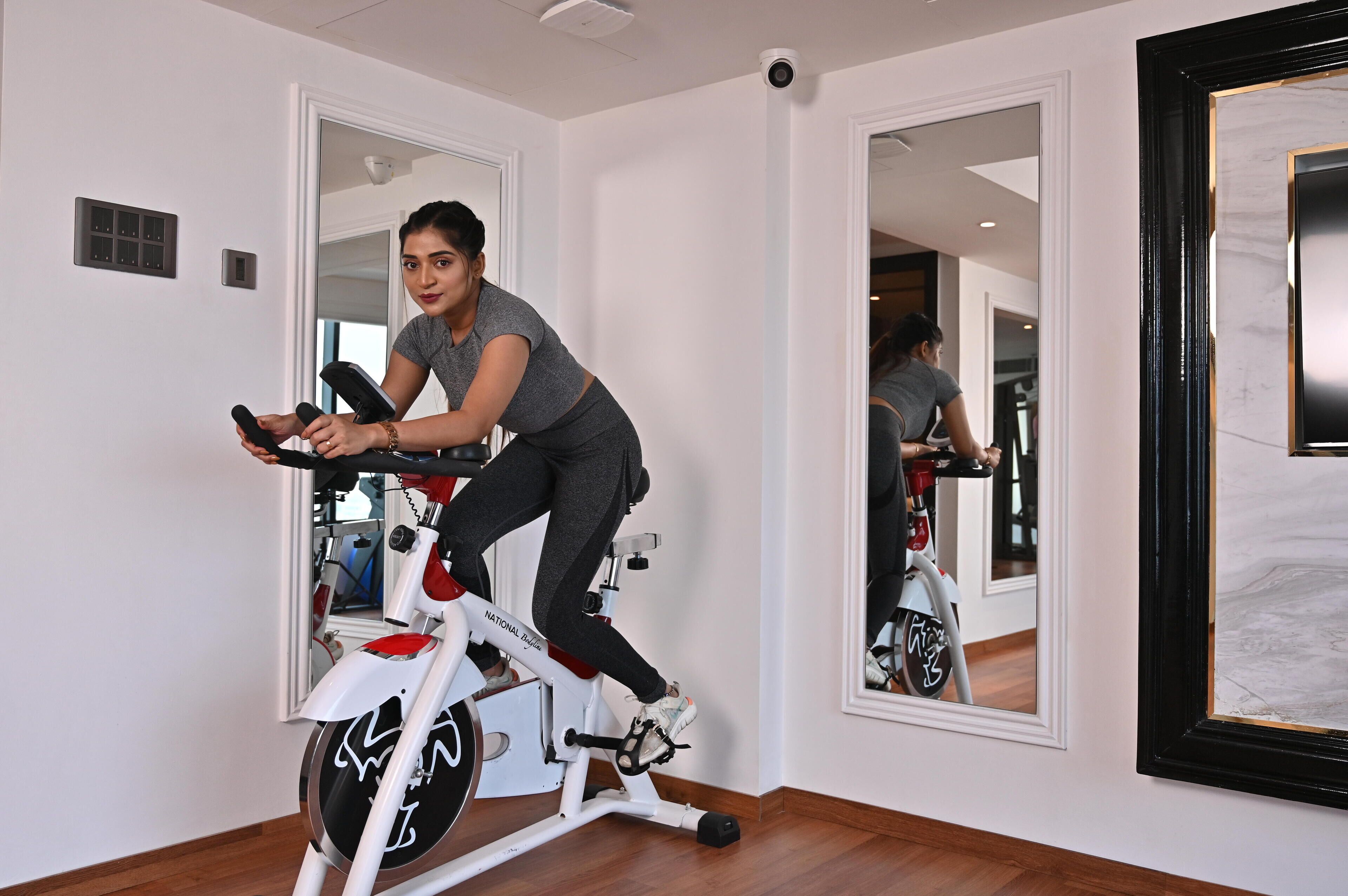 Una persona usando una bicicleta estática en una habitación con un espejo, una puerta y un interruptor de luz en la pared.