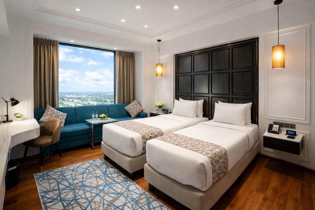 Habitación de hotel con dos camas, un sofá, un escritorio y vistas a la ciudad.