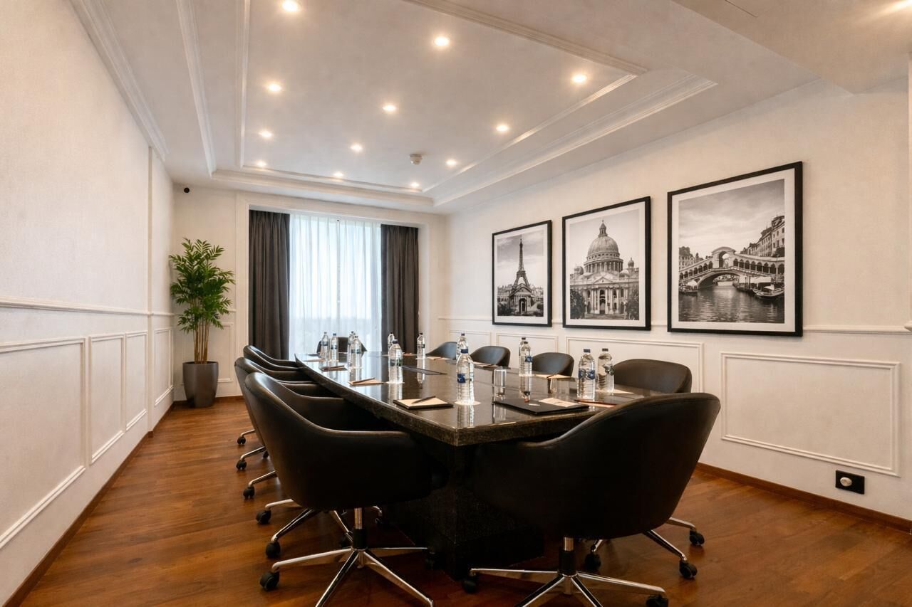 A conference room with a long table, black chairs, and framed pictures of famous landmarks on the wall.