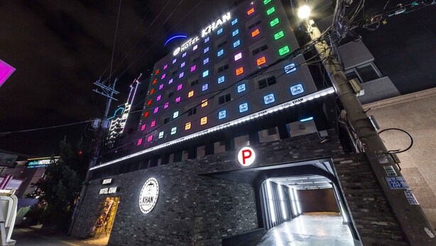 A multi-story hotel with a prominent sign reading "Hotel KHAN" and a parking sign below. - Design Hotel Khan (Suwon)
