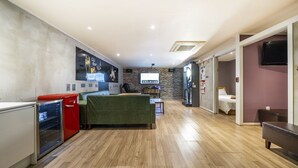 A modern hotel room with a kitchen area, a green sofa, a small table, and a TV mounted on the wall. - Design Hotel Khan (Suwon)