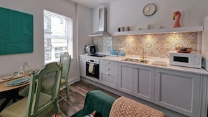 Una cucina compatta con zona pranzo, dotata di forno a microonde, bollitore e una decorazione a forma di fenicottero.