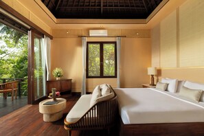 A spacious bedroom with a large bed, a wooden bench, and a view of lush greenery through a sliding door. - Villa Leona Ubud (Ubud)