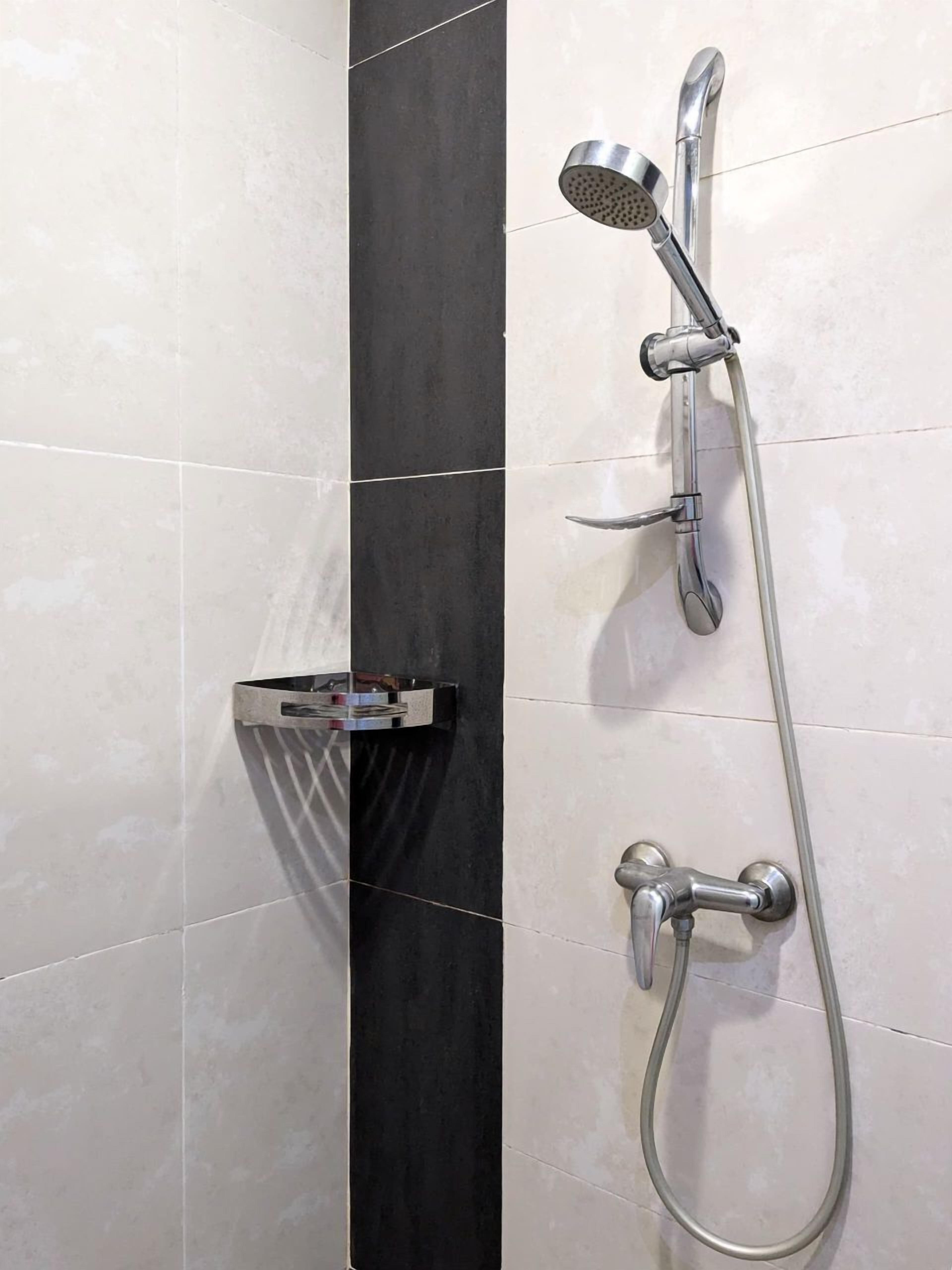 A modern shower with a handheld showerhead and a wall-mounted faucet.