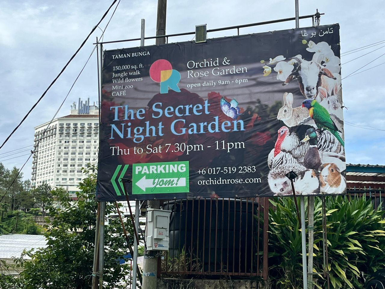 A billboard advertising The Secret Night Garden with operating hours and contact information.