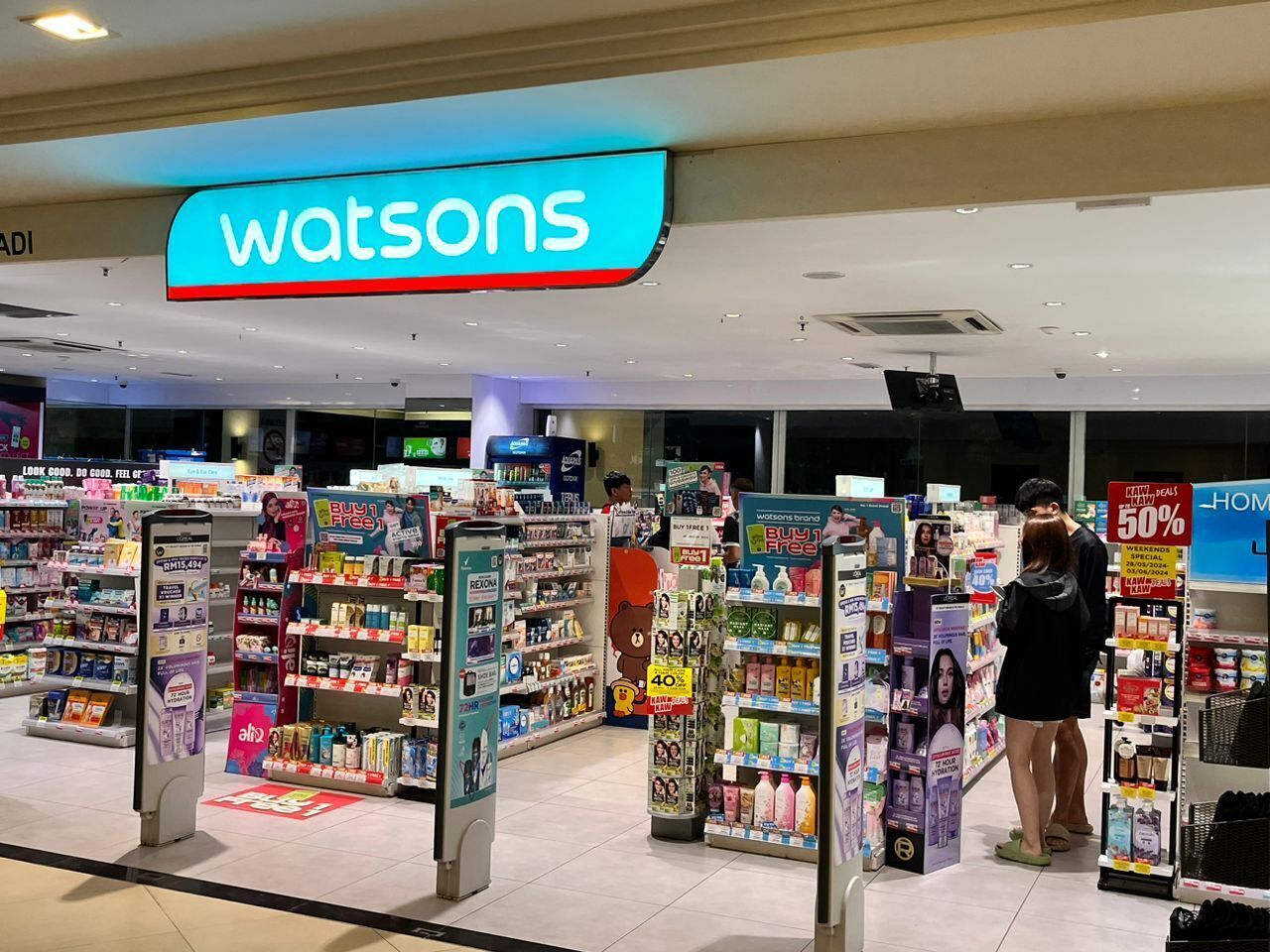 A Watsons store with multiple aisles of products, promotional signs, and a clear ceiling.