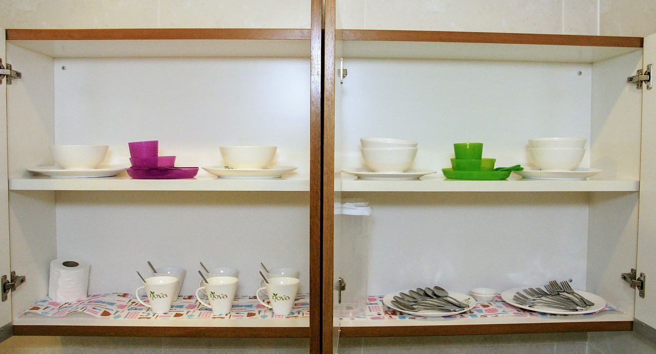 Habitación con dos armarios blancos, cada uno con cuencos, platos y tazas.