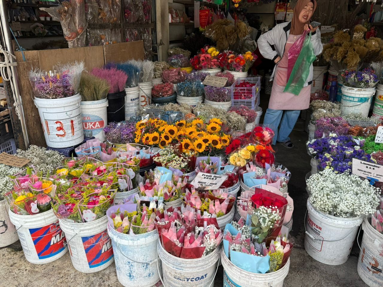 A flower market with various types of flowers displayed in buckets and baskets.