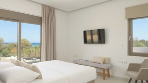 A modern hotel room with a large bed, a bench, a chair, and a TV. - Costa Villa , Walk to Sandy Beach & Heated Pool (88XM+XWC Pirgos)