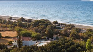 A coastal property with a swimming pool, surrounded by trees and a view of the sea. - Costa Villa , Walk to Sandy Beach & Heated Pool (88XM+XWC Pirgos)