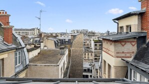 A view of a cityscape with multiple buildings, including a prominent stone tower and various residential and commercial structures. - 1. Studio Porte Dauphine Paris 16ème (Paris)