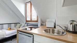 A compact kitchen with a built-in dishwasher, a sink, and a kettle. - Studio Porte Dauphine Paris 16ème (Paris)