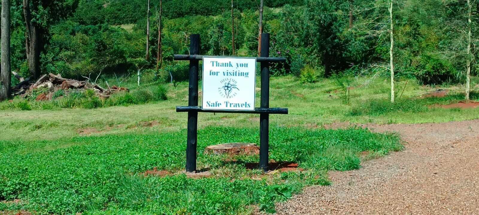 Un panneau affichant un message de remerciement à l’intention des visiteurs, placé dans un cadre naturel, avec de la verdure et un sentier de terre.