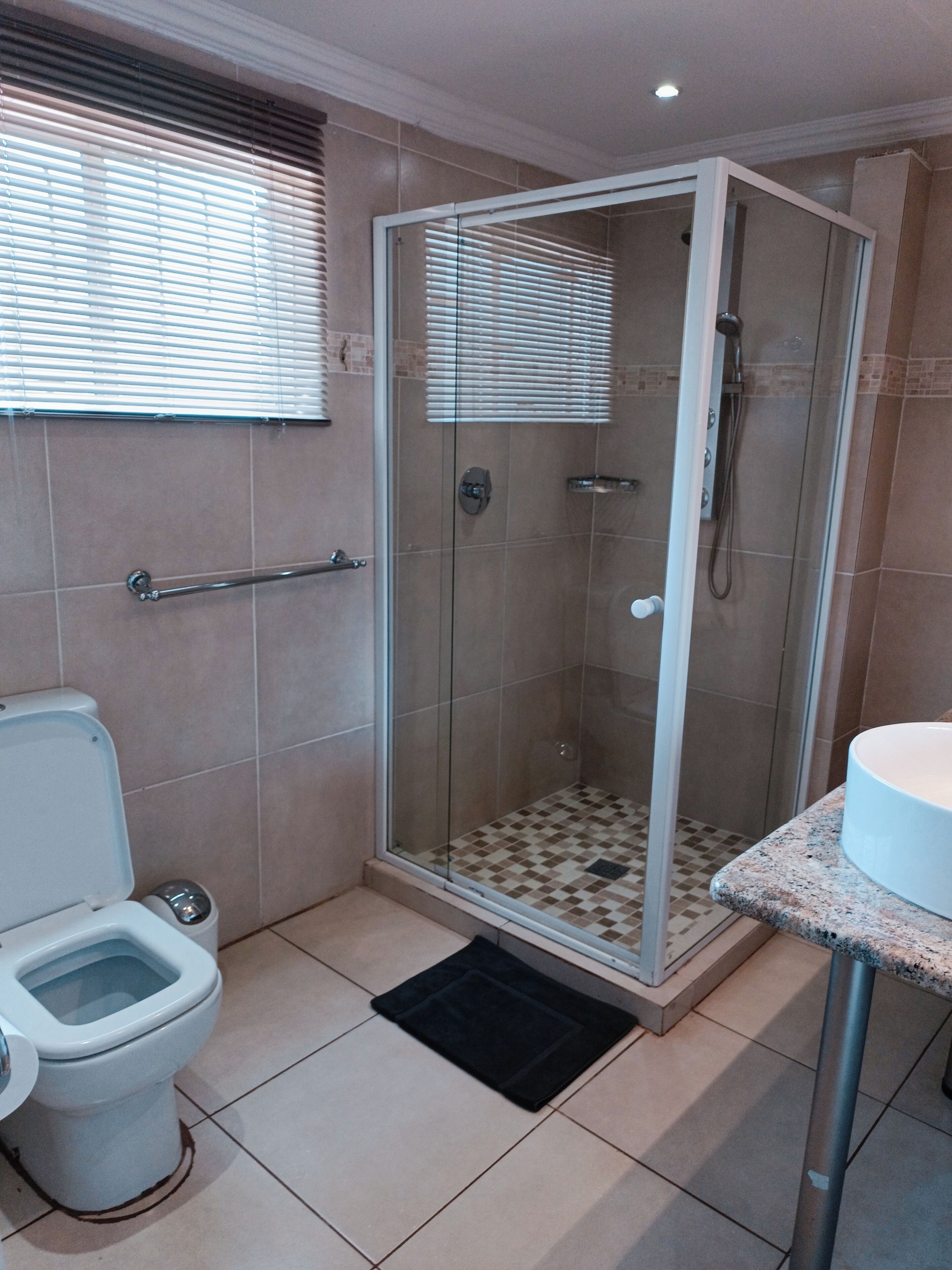 Een badkamer met een glazen douchecabine, toilet en wastafel.
