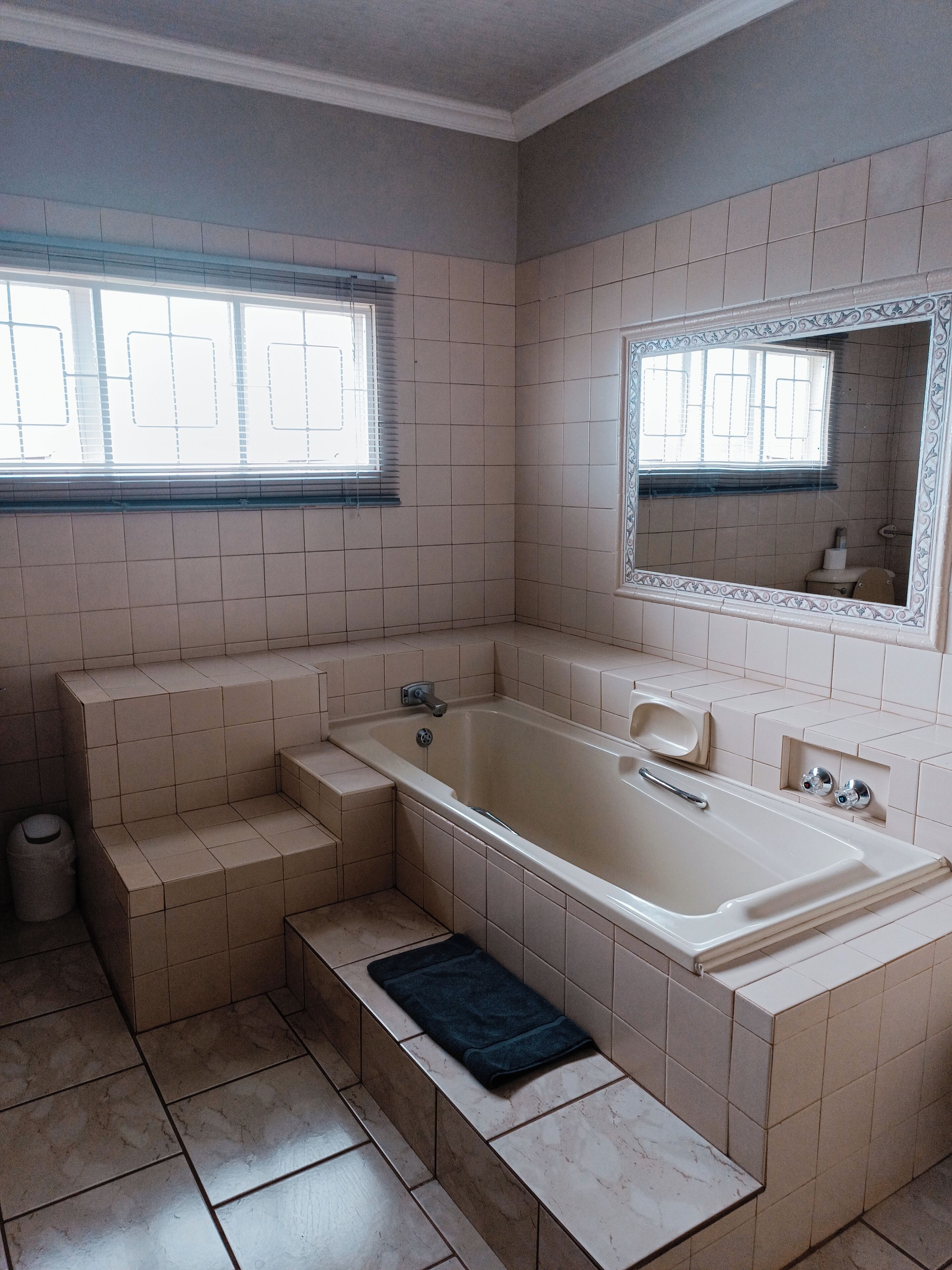 A bathroom with a bathtub, a window, and a mirror.