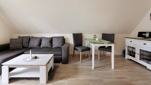 Una sala de estar moderna con un sofá modular, una mesa de comedor y una kitchenette.