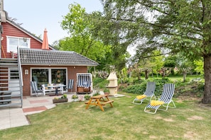 A backyard with a patio, a table, chairs, a small playhouse, and two lounge chairs. - Apartment 'Ferienwohnung Sven' with Shared Garden and Wi-Fi (Langenhorn)