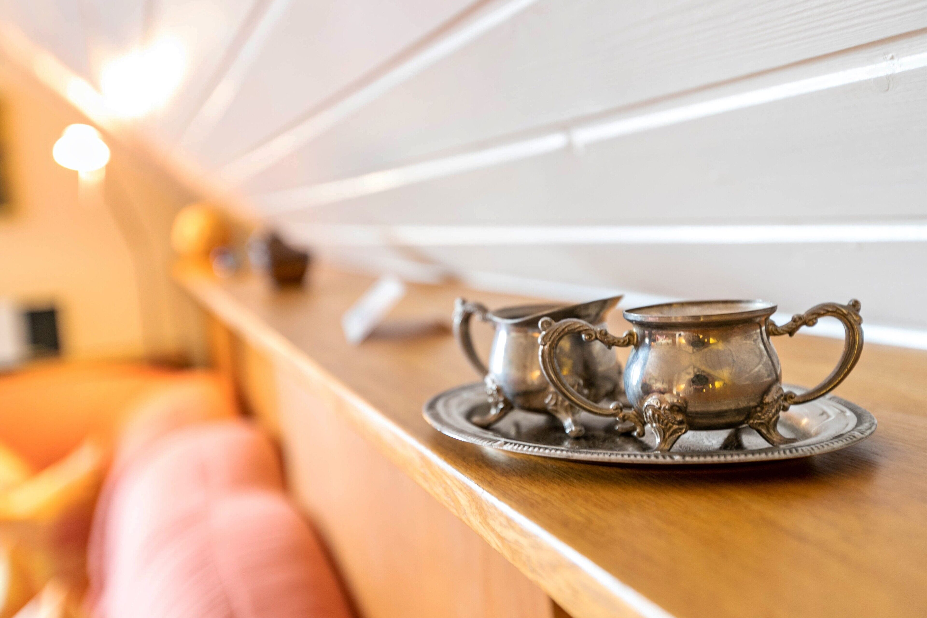 A metal tray with two silver cups on a wooden surface.