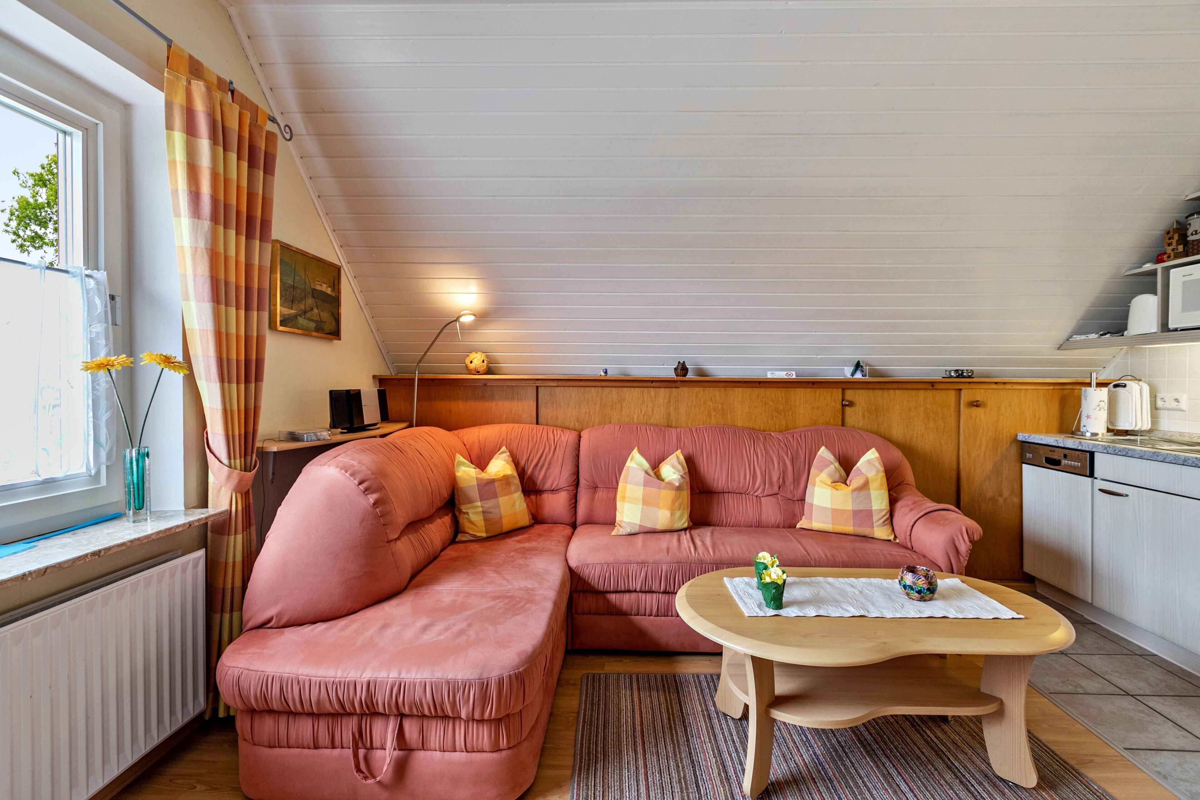 A cozy living room with a sectional sofa, a small round table, and a window with curtains.