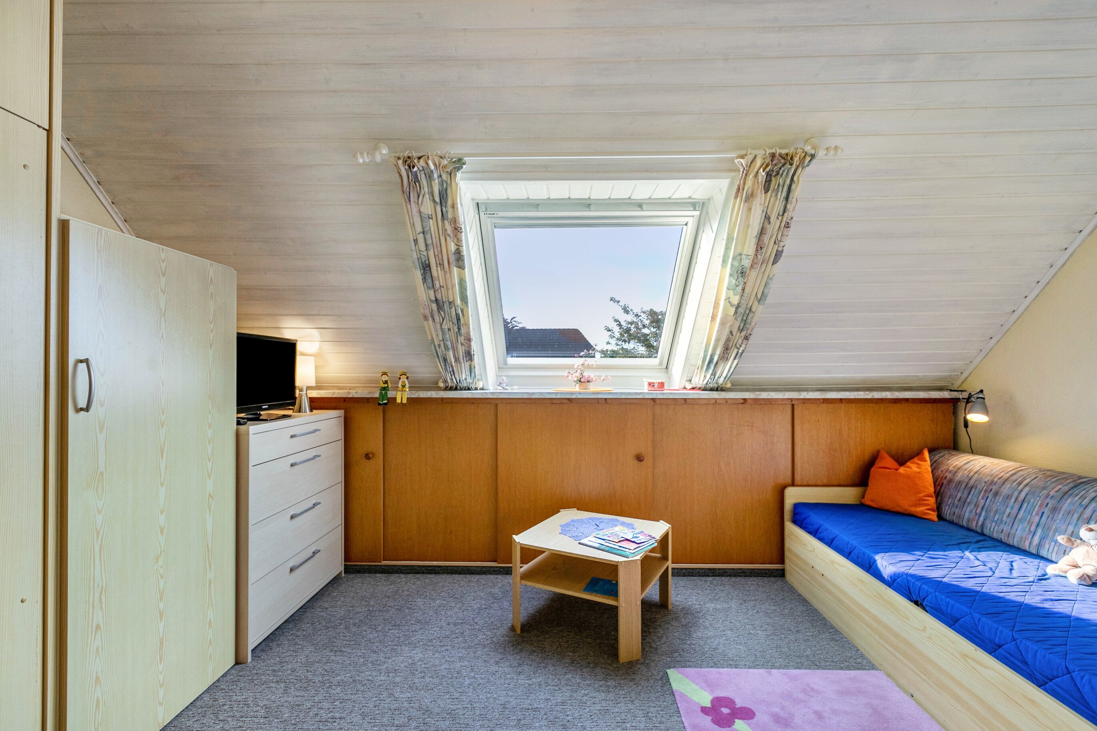 Una habitación con cama estilo altillo, un escritorio, una mesita y una ventana con cortinas.